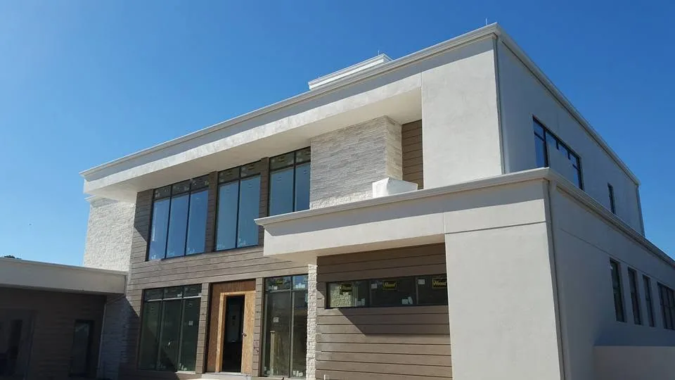 Flat roof modern stucco home under construction fascia gutters wood siding sanfo